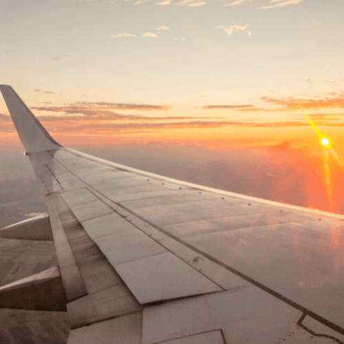 Airplane wing in flight against a clear blue sky, capturing the essence of travel and adventure.