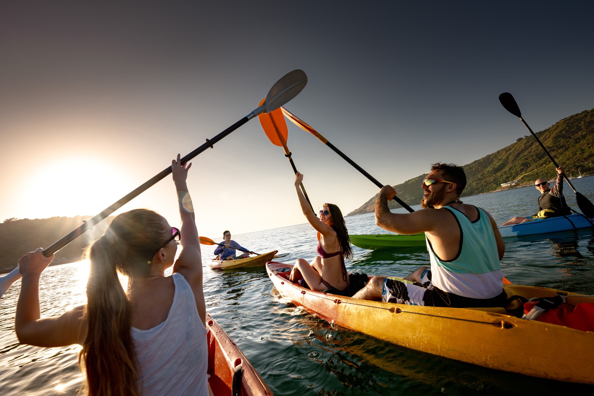 Big group of happy friends are kayaking at sunset sea